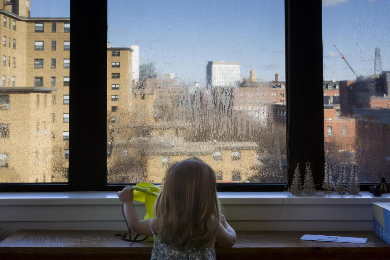 toddler looks out at city from foggy windows