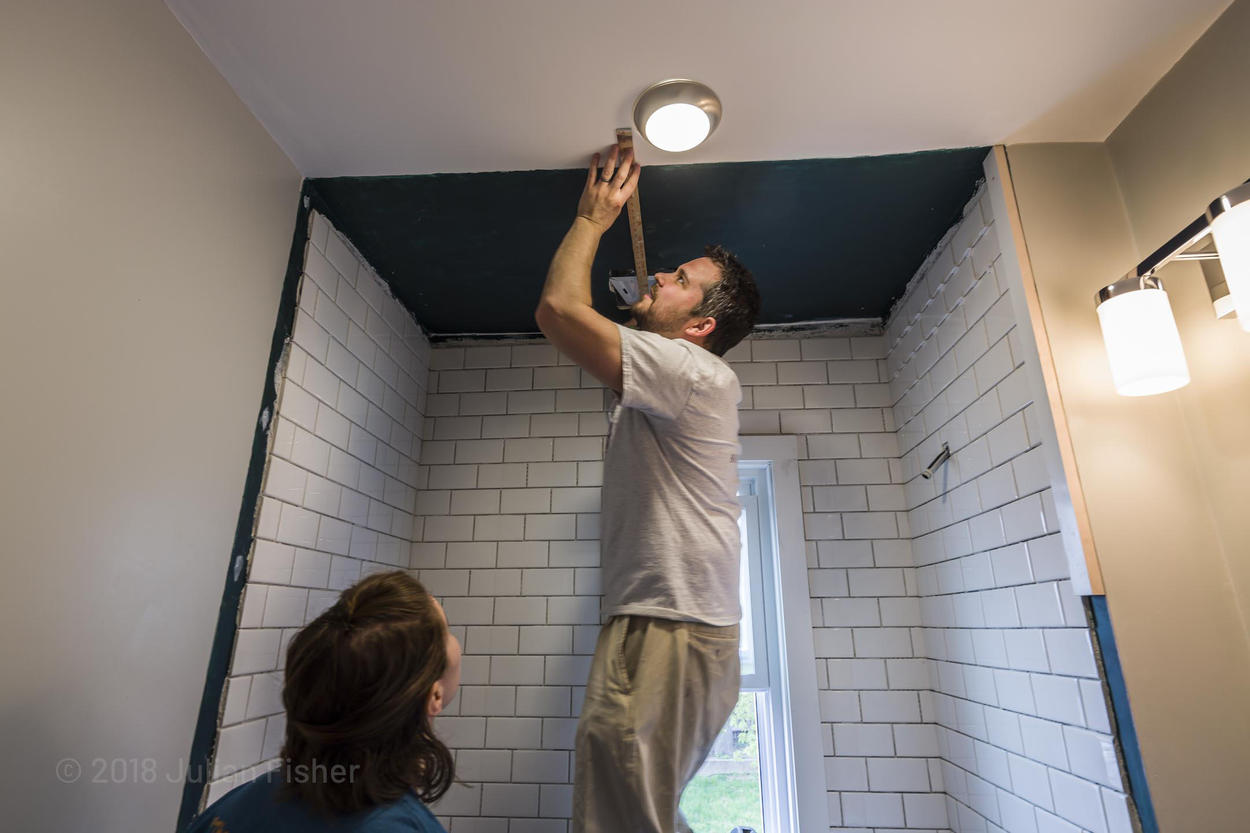 man installs new light in bathroom